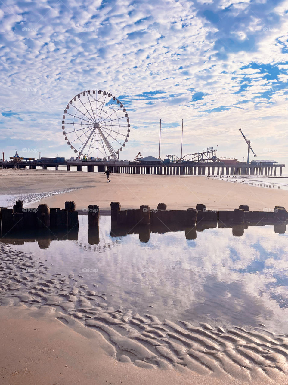 Ferris wheel on pier with mirror reflection of sky wheel and wooden pier 