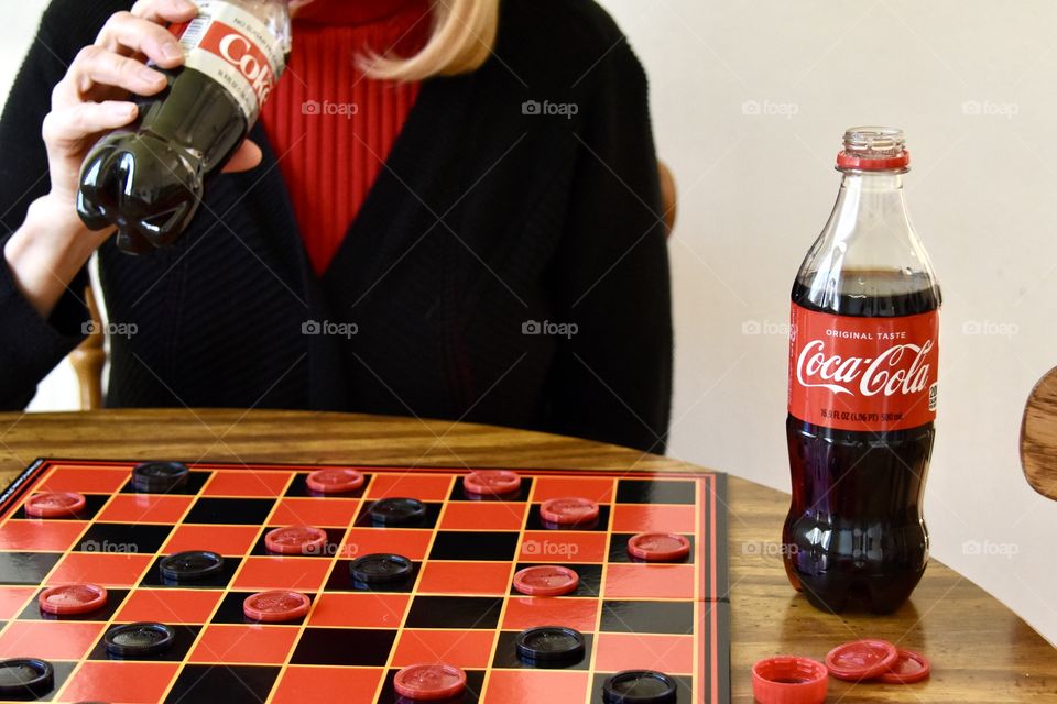 Woman drinking Diet Coke and playing checkers 