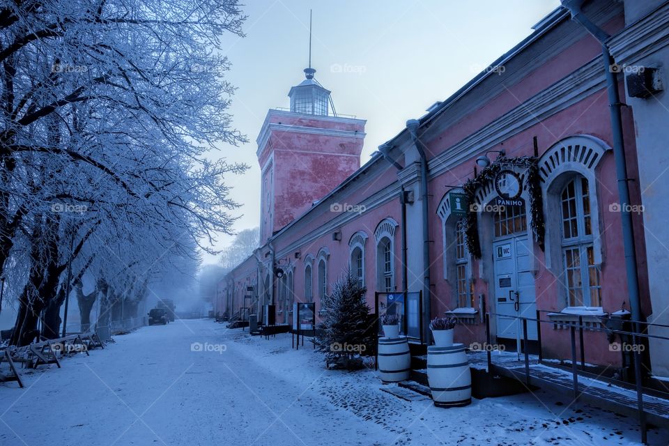Helsinki, Finland - January 5, 2016: Imperial Russian era historical jetty barracks and the clock tower on cold and foggy January winter morning in Helsinki, Finland. Jetty barracks provide the main entrance to the Suomenlinna fortress island. Also Suomenlinna beer brewery and brewery restaurant currently operate in the barrack premises. Bastion fortress in the island has been added in the UNESCO World Heritage List and it is one of the main tourist attractions of Helsinki. Photo taken: January 5, 2016.
