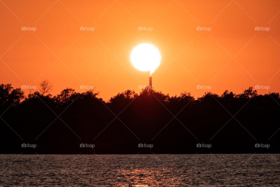 A question mark formed by the sunset and the fire from the factory chimney