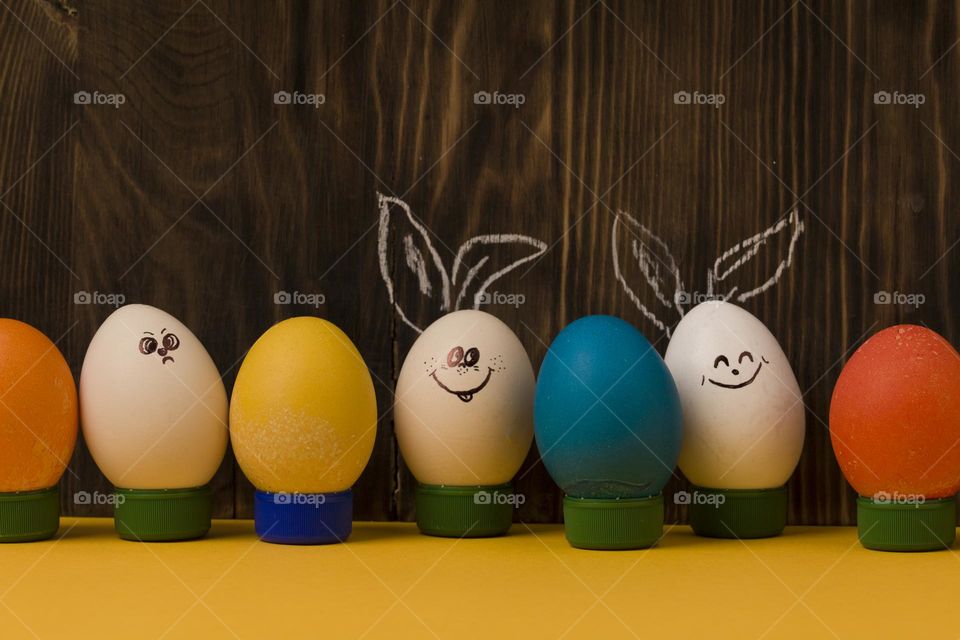 Funny smiling smileys eggs on dark wooden background
