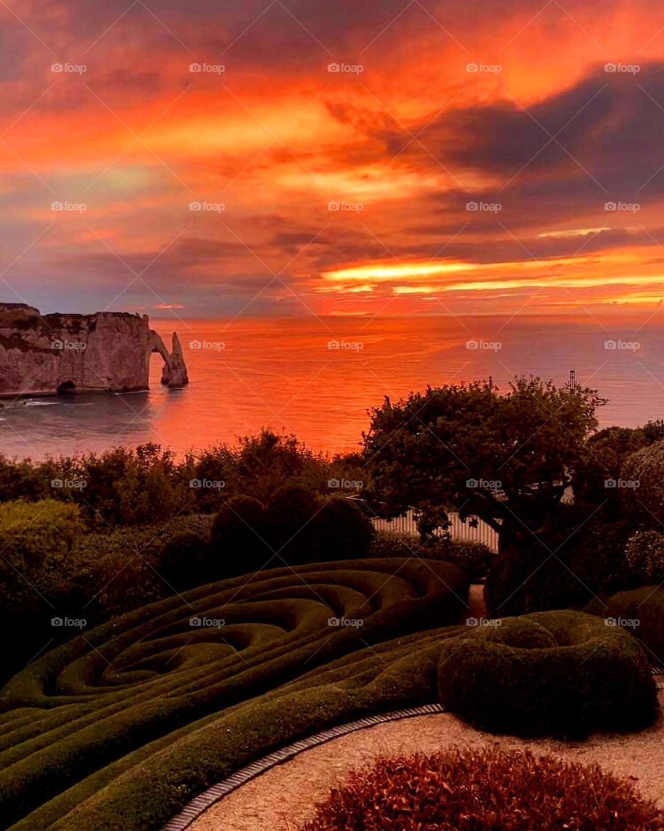 Panoramic view of the Alabaster's coast's cliffs and of the channel from neo-futuristic Etretat's gardens under a sunrise's orange colour explosion