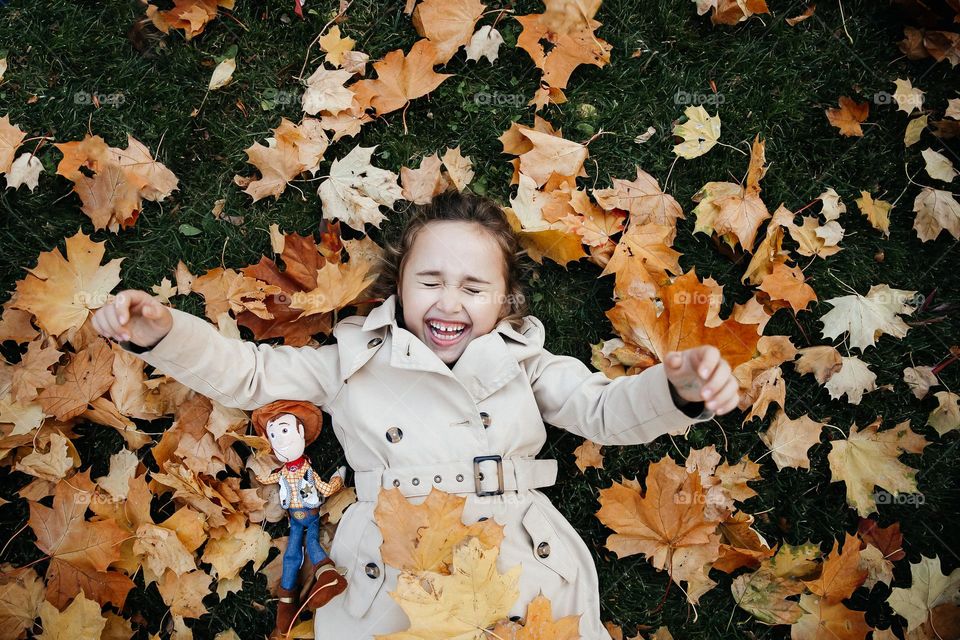 Small girl smiling in fall autumn leaves