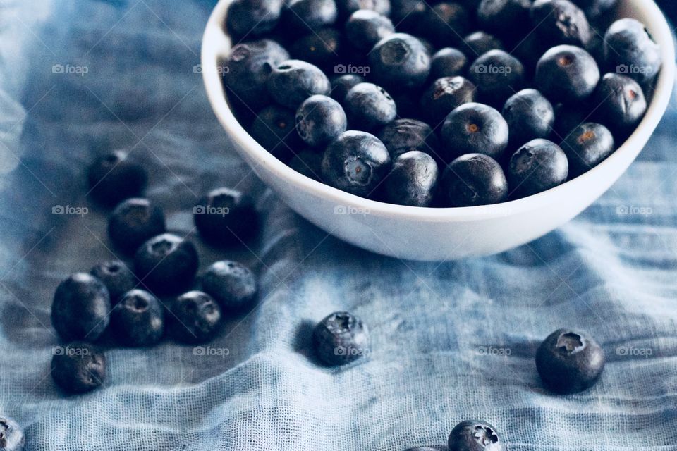 Fruits! - Blueberries in a white bowl and scattered on graduated blue fabric  