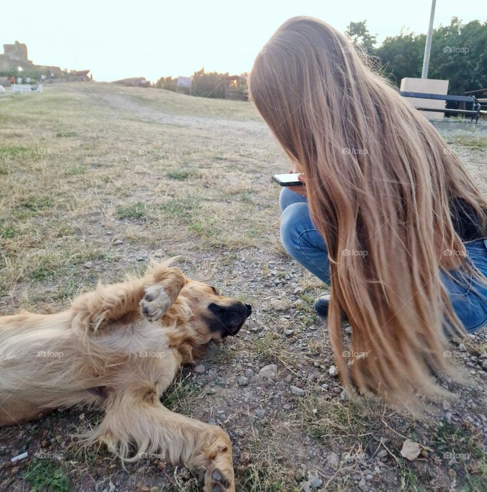 young girl with long blond hair playing with a dog