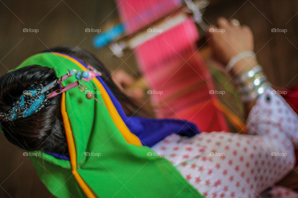 Rear view of woman weaving thread at industry