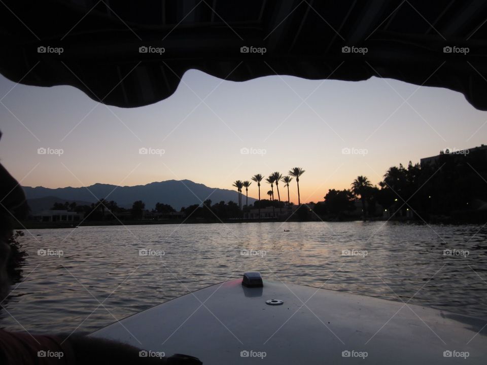 Front of boat on a lake at sunset.