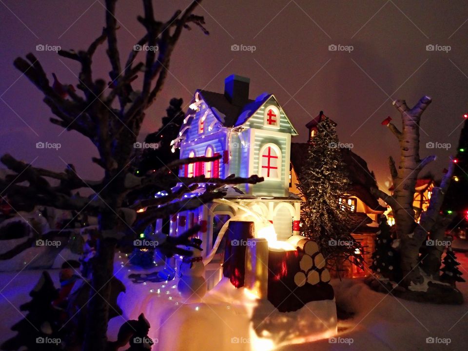 A little house and tree on display in a Christmas village 