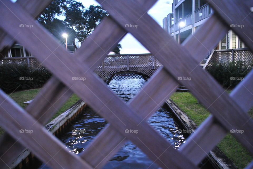 Water and bridge seen through a fence