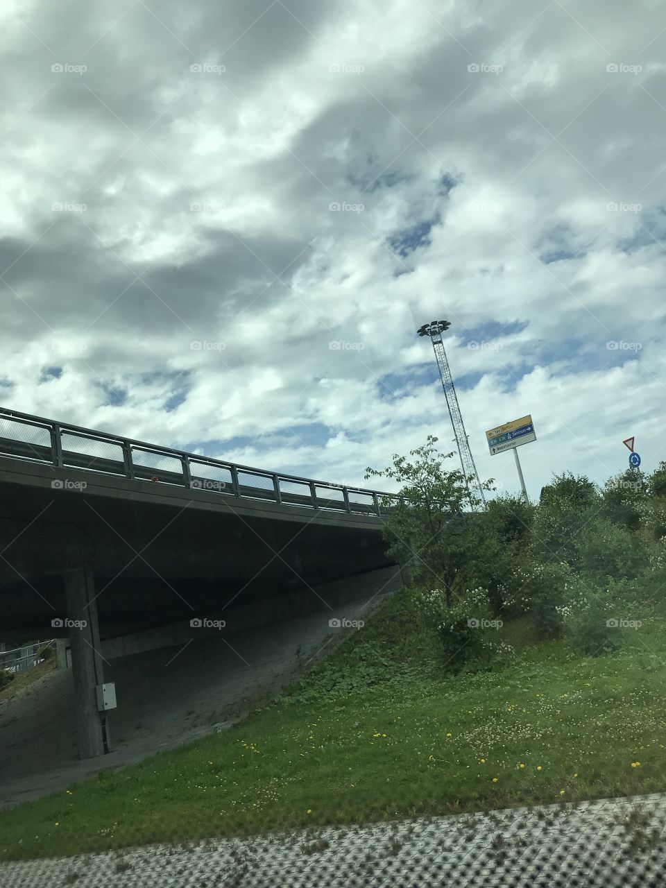 The beautiful skies over an road-bridge. The skies is very grey, but a little bit blue comes through the heavy clouds
