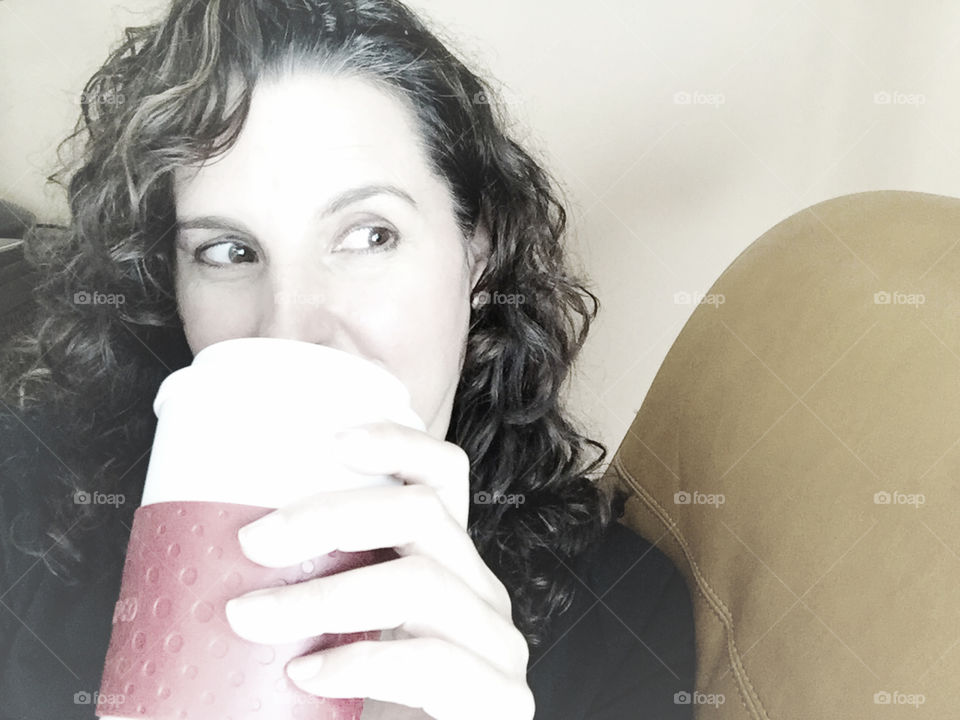 Woman drinking coffee to go from red and white travel mug 