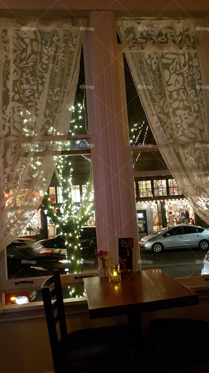 evening urban scene scene through lace curtained window and romantic table fot two setting