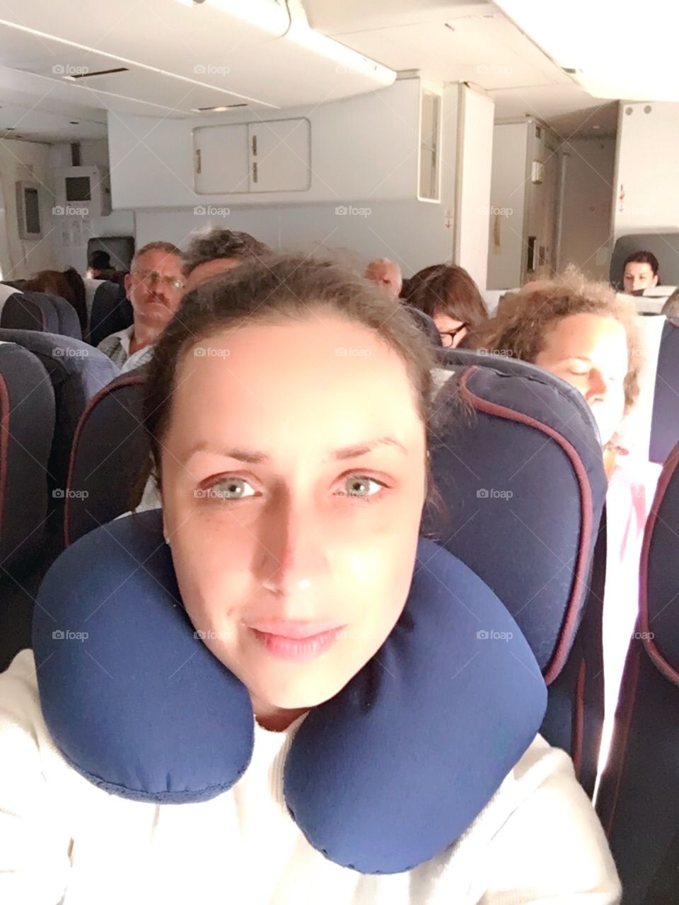 young girl sitting in the seat of the plane with a pillow under the neck