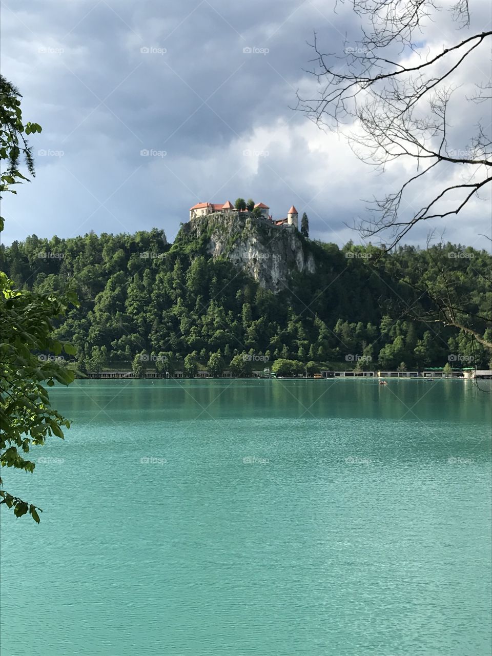 Magical fairytale castle on mountain top looking over pristine glacial Lake Bled. Fairytale scene. Dramatic sky. Magical nature.