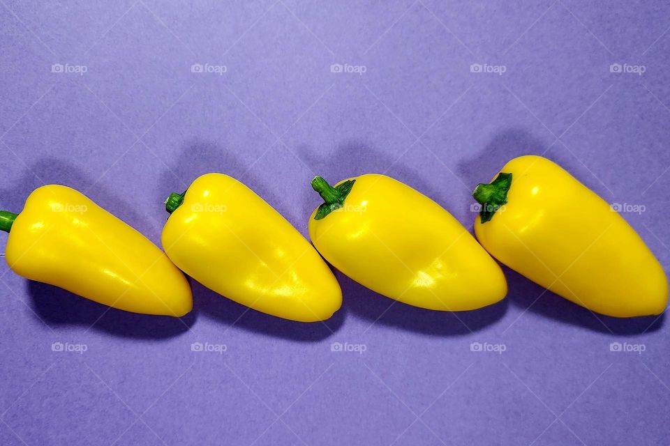 Yellow and purple complementary colours flatlay with yellow small peppers on a purple surface