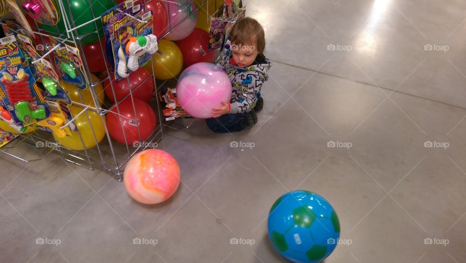 Boy playing with balls at store.