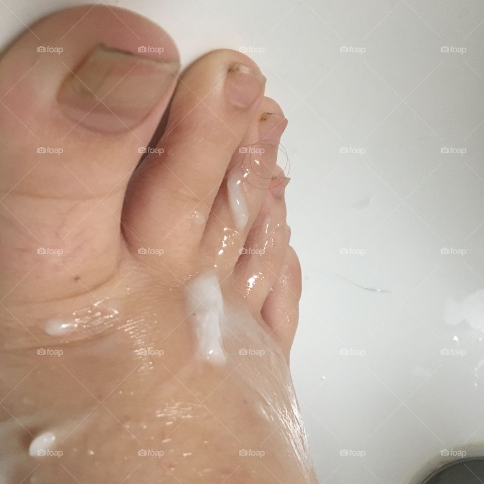 This is a picture of my foot, mostly toes. There's a liquidy creamy white substance smeared on my foot. Background is my white porcelain bathtub. I'm white and my toes are dirty and unkempt. I'm also young-- no wrinkles, smooth skin, one freckle.