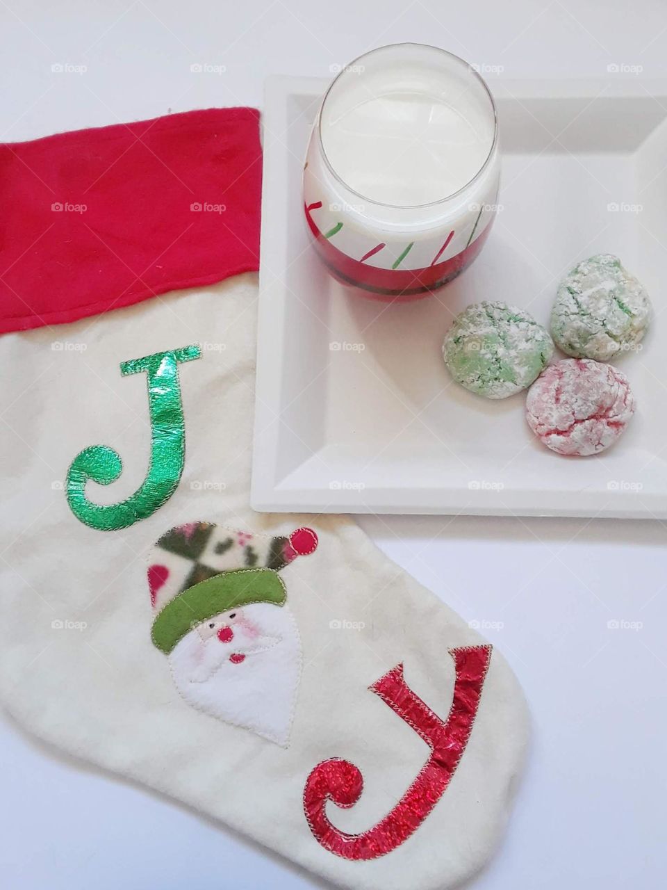 Christmas cookies and a glass of milk are left out for Santa. Next to the plate is a Christmas stocking with the word joy on it.