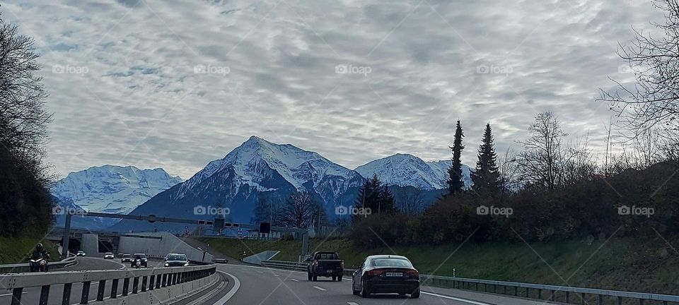view of the cars against the high mountains range and clouded sky