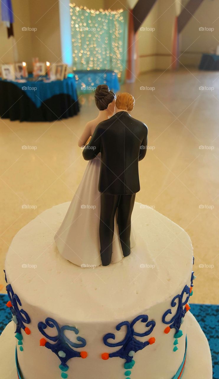 An enbracing couple cake topper looks out over the reception hall waiting for guests to arrive after the wedding ceremony.