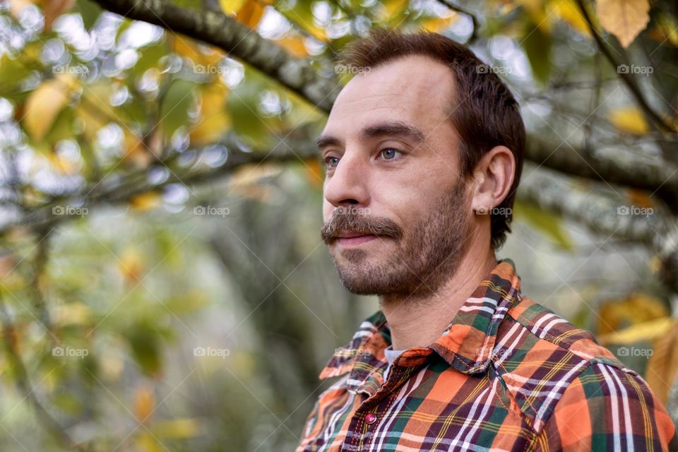 Man with moustache and light beard under autumnal trees