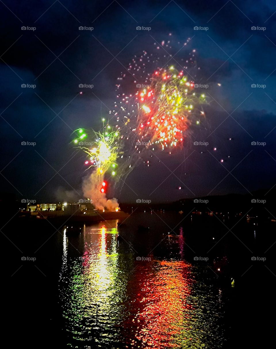 Red and green fireworks reflection on water