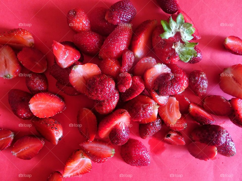 sliced strawberries on red background