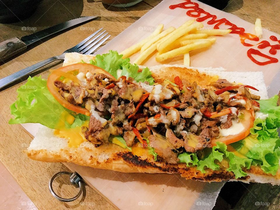 Philly cheesesteak sandwich with fries on the side