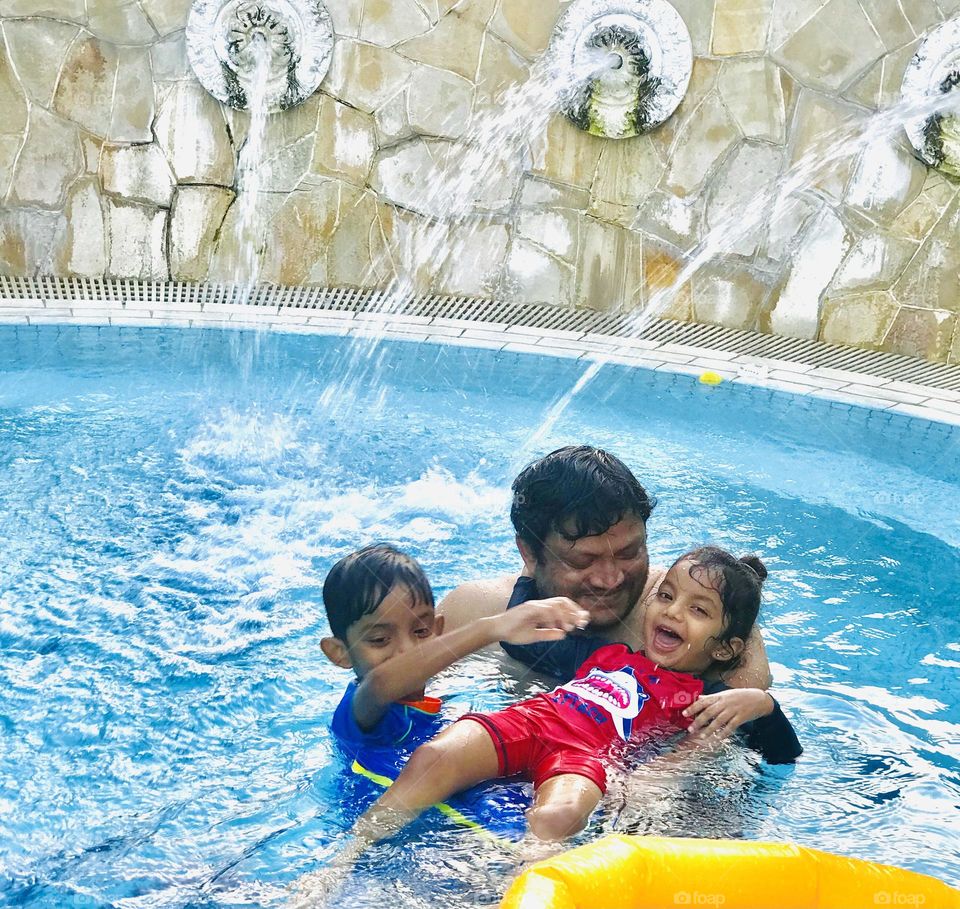 Father and son and daughter together enjoying at swimming pool 