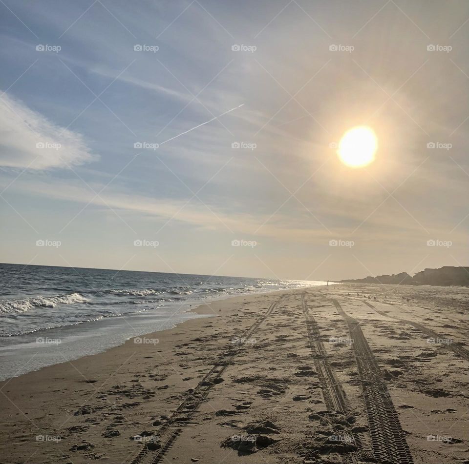 Sun shining on Tire Tracks on Sandy Beach of North Carolina’s Beautiful Crystal Coast. 