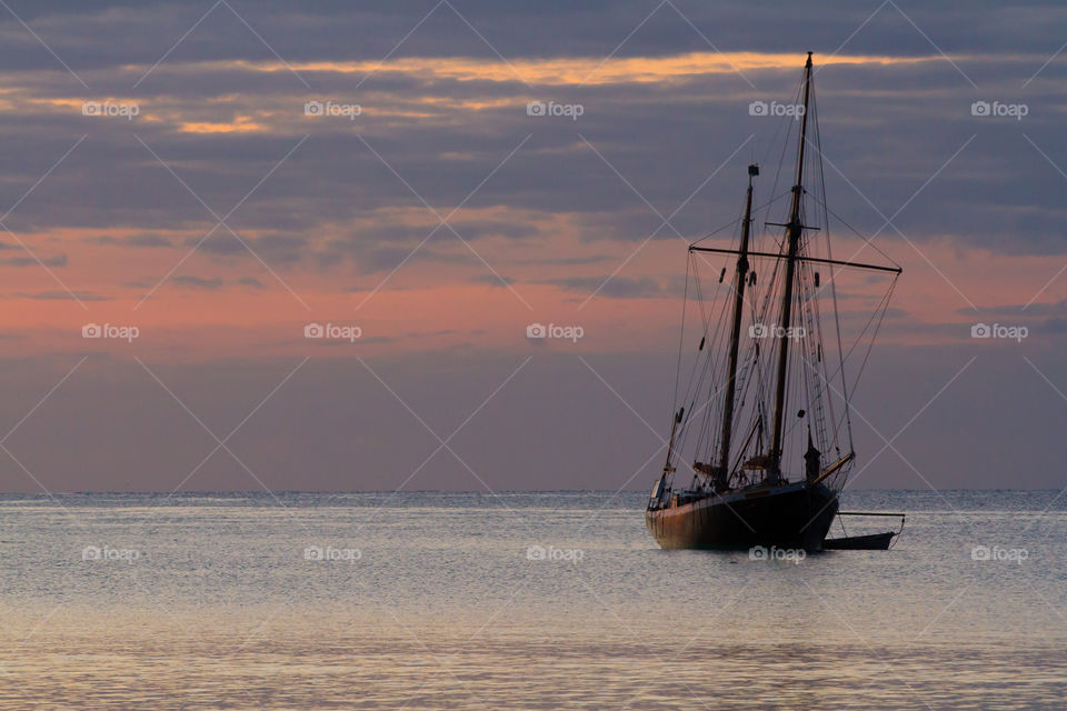 Sailboat Sunrise. A sailing boat moored on a calm Ocean at sunrise