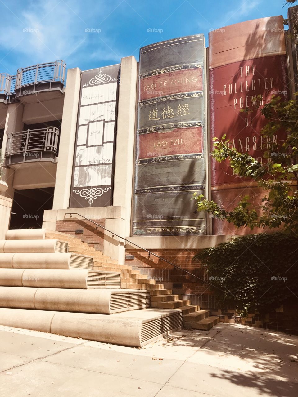 Gorgeous wall mural on library in Kansas City, MO of books lined up and the building is even complete with books stacked on each other for steps!! 