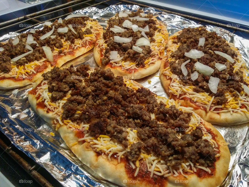 Homemade sausage and onion pizza on Naan bread ready to be baked in the oven