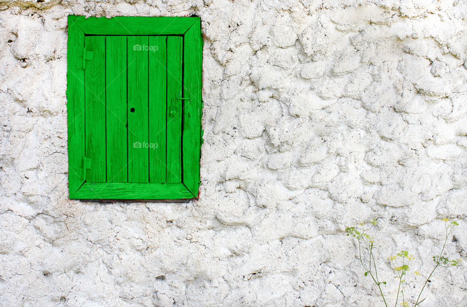 Green window on white textured wall, exterior