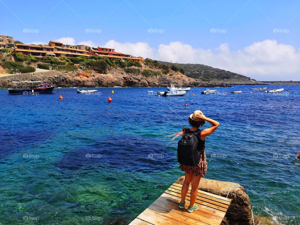 tourist from behind looks at the wonderful sea of ​​the island of Giannutri in Tuscany