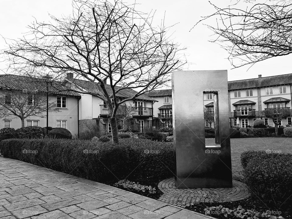 black and white photo of houses and a metal art sculpture