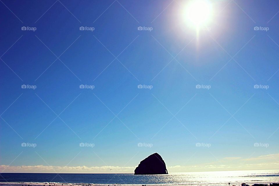 The sunshining down on haystack rock as it rests majesticly in the ocean in Pacific City Oregon.