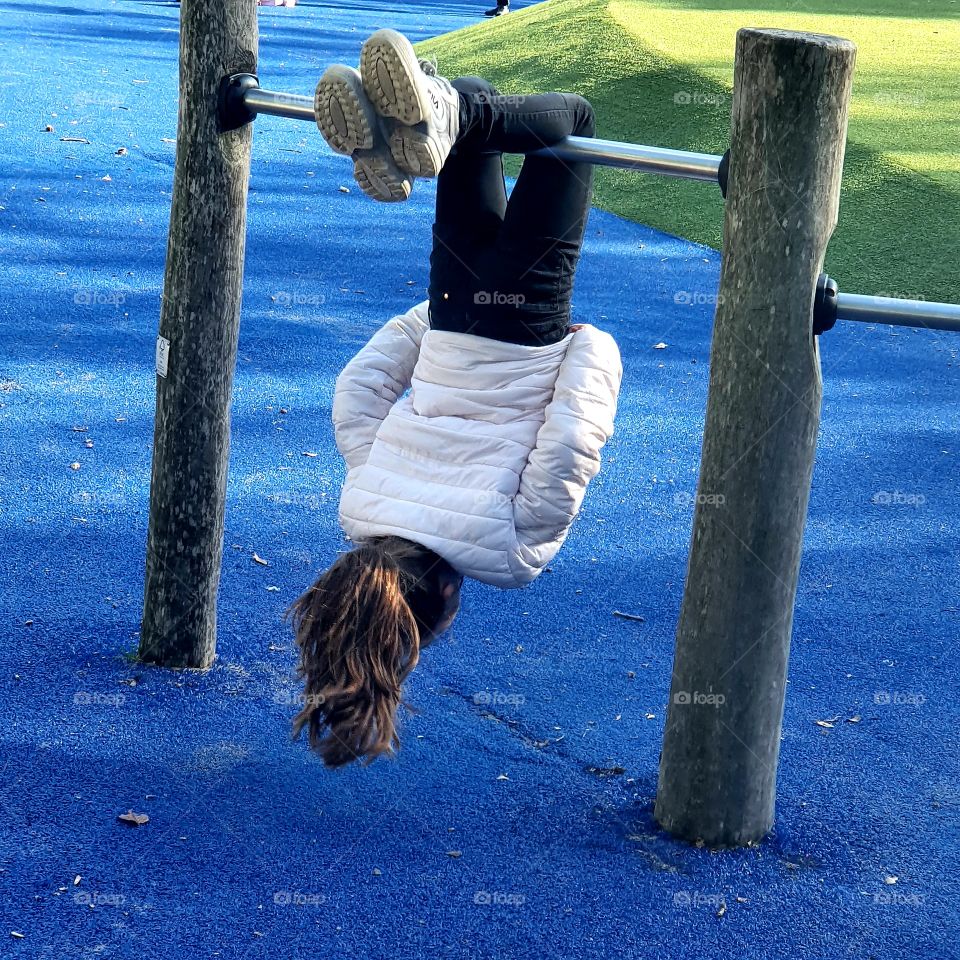Girl hangs in climbing frame