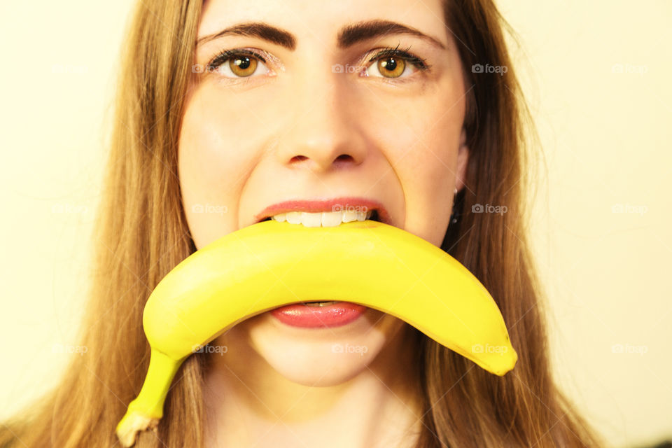 A young lady with a healthy banana in her mouth