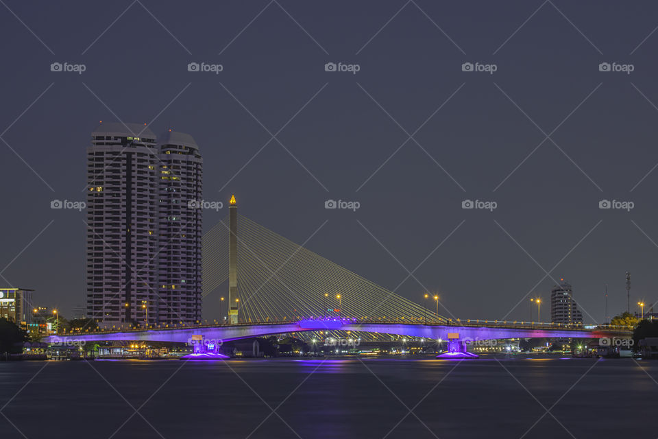 The beauty of colorful lights on Pinklao bridge and cars driving at Night on Chao Phraya River, Bangkok in Thailand.