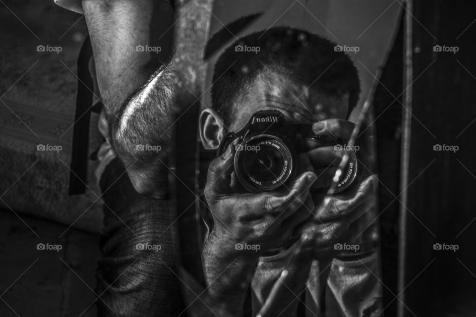 Portrait with a Nikon camera on a mirror in black and white.