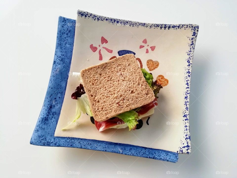 Sandwich made with square slices of bread and placed on a square plate