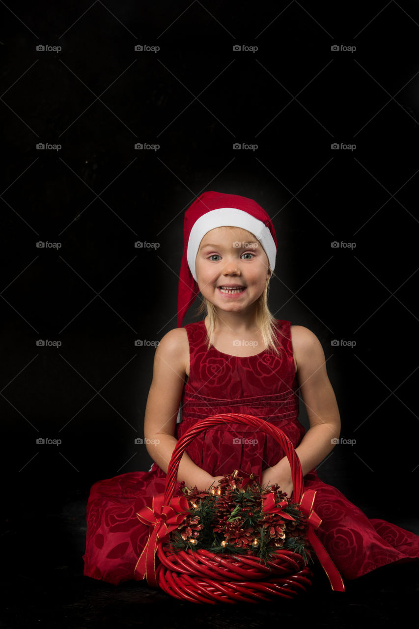 Four year old girl posing in santa dress for christmas.