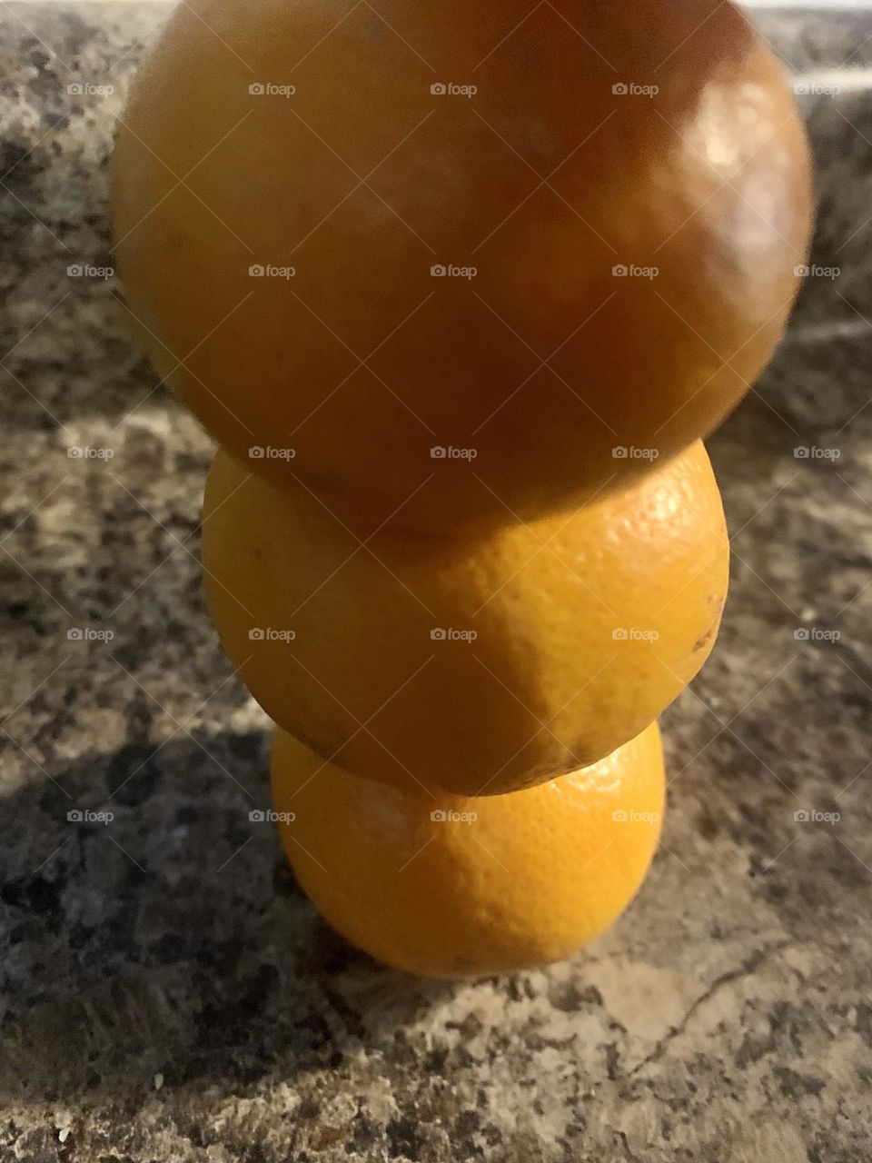 3 oranges stacked high making shadows on kitchen counter