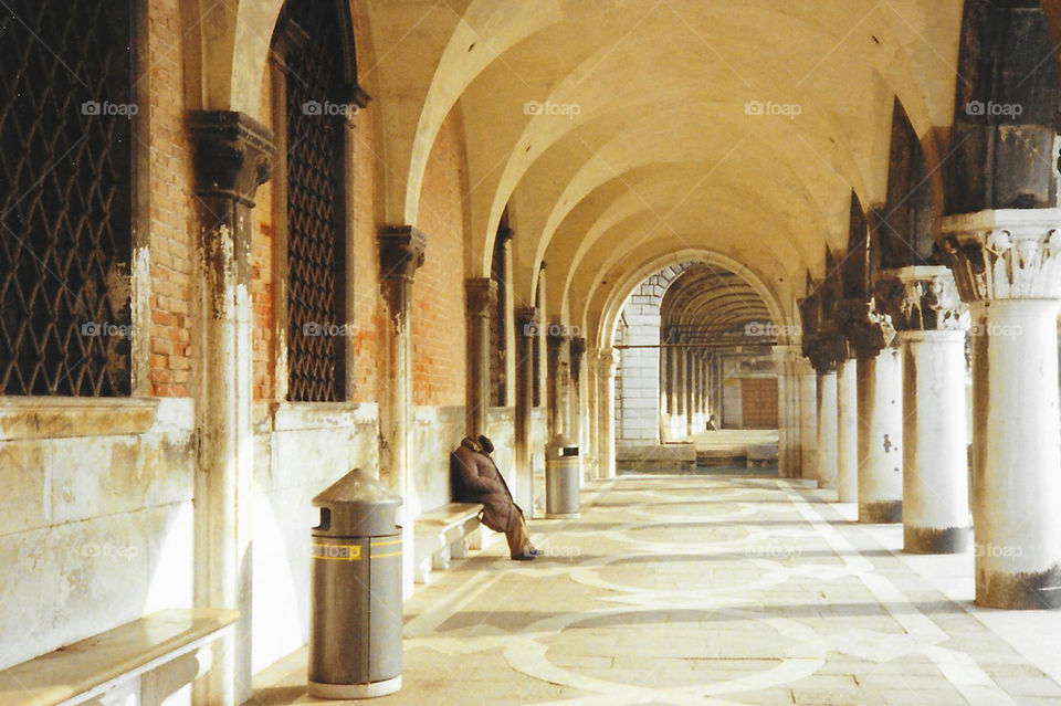 A column lined corridor off a Piazza, I think della Rotonda. A bit of old and new. An old man weary, resting on a bench. The worn & stained ancient architecture & the modern aluminum garbage cans. 