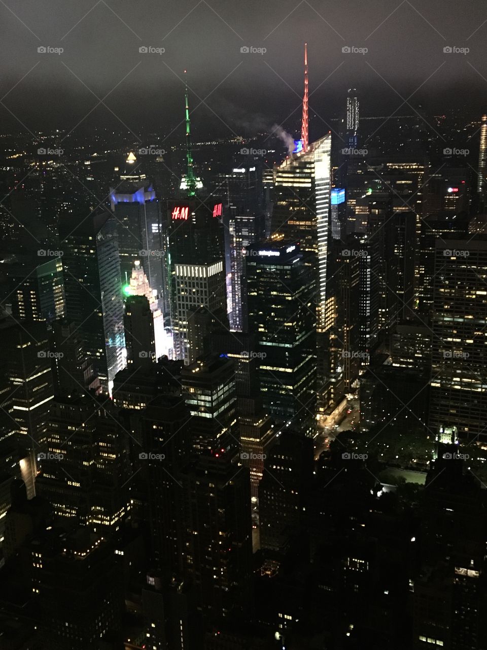 The lively, bustling city of New York on a summer night. View from the Empire State Building Observatory Deck. Flashing Times Square seen in the distance. 