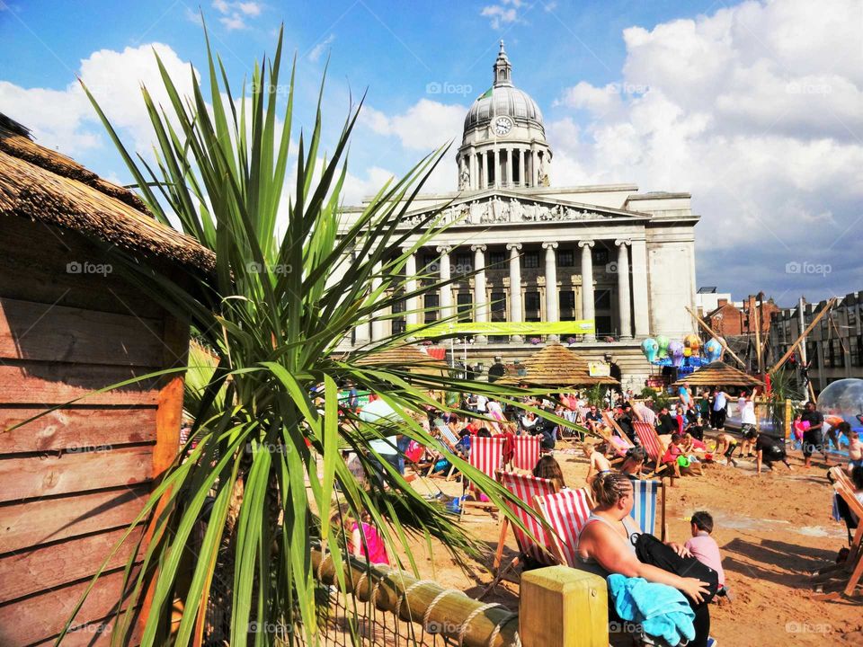 People enjoying good weather on the artificial beach in the Old Market Square with the Council House in the background, Nottingham, England, UK