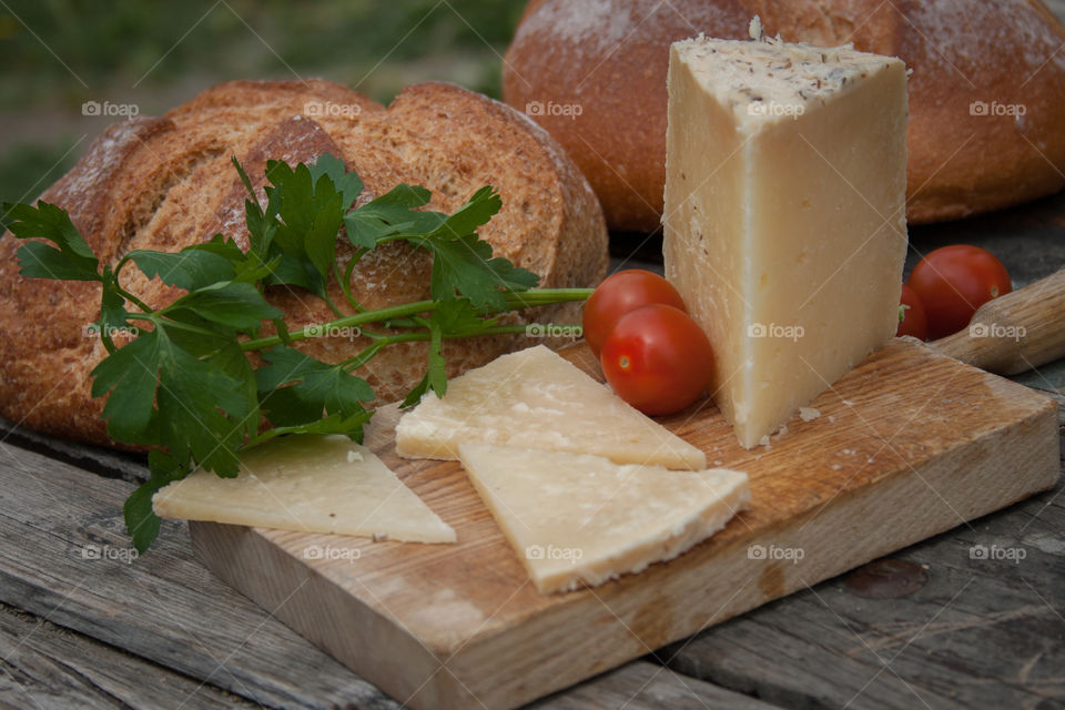 Slices of cheese on the table with bread and cherry tomatoes 