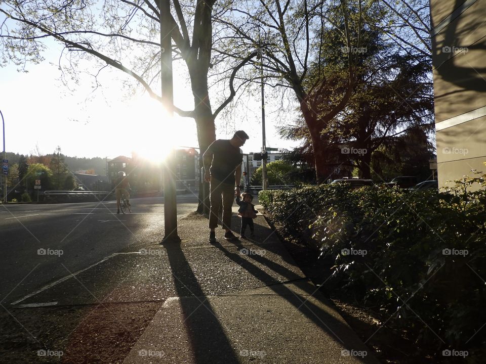 Father daughter walking down the street. Todd long along a busy street in the city. Love the golden hours in Portland. The trees and the lush green bushes. 
