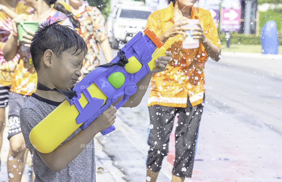 Asian boy holding a water gun play Songkran festival or Thai new year in Thailand.